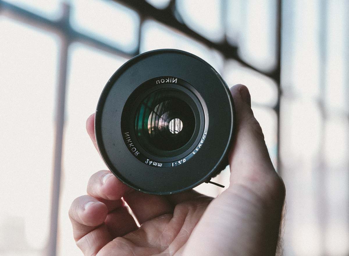 camera lens person holding black Nikon camera lens photography